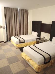 a hotel room with two beds and a window at Shervinton Executive Boutique Hotel in Tawau