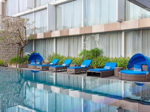 a row of blue lounge chairs next to a swimming pool at ARTOTEL Suites Bianti Yogyakarta, CHSE Certified in Yogyakarta