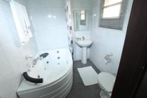 a bathroom with a tub and a toilet and a sink at Room in Lodge - Prince Of Anthony 1960 Hotel-apartment in Lagos