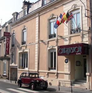 un'auto rossa parcheggiata di fronte a un edificio di Hotel Le Charleston a Le Mans