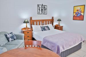 een slaapkamer met een bed, een bank en een tafel bij Central Park Motel in Rockhampton