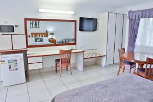 a room with a desk and a table and a kitchen at Central Park Motel in Rockhampton
