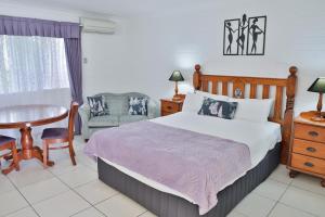 a bedroom with a bed and a table and a chair at Central Park Motel in Rockhampton