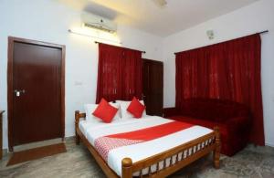 a bedroom with a bed with red curtains and a couch at Krishna Kailas in Guruvāyūr