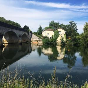 a bridge over a river with houses and trees at Petit Boudoir The Riverside Retreat in Triac-Lautrait