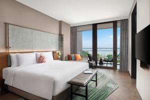 a bedroom with a large white bed and a living room at Hotel Indigo Suzhou Yangcheng Lake, an IHG Hotel in Suzhou
