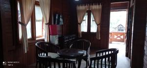 una sala da pranzo con tavolo, sedie e finestre di Bungalow kampoengstrawberry ciwidey a Ciwidey