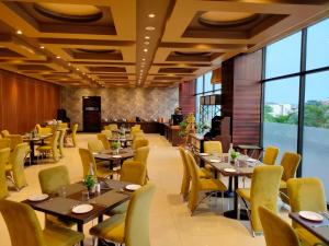 un restaurante con mesas, sillas y ventanas grandes en Comfort Hotel Vista en Lucknow