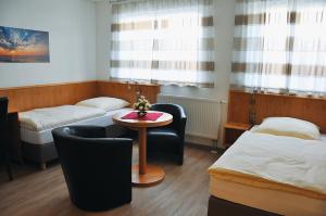 a room with two beds and a table and chairs at Garni Hotel Alber in Marktl