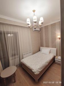 a bedroom with a bed and a table and a chandelier at Altyn in Astana