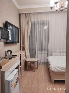 a hotel room with a bedroom with a bed and a television at Altyn in Astana