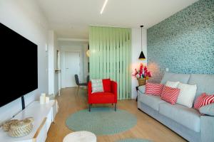 a living room with a couch and a red chair at La Casita del Muelle in Melenara