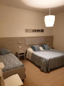 a hotel room with two beds and a light at Hotel Lucerna in Castiglione della Pescaia