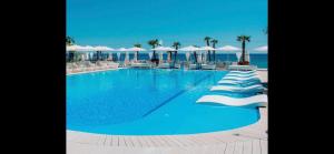 a large blue swimming pool with white umbrellas and the ocean at Arcadia in Odesa