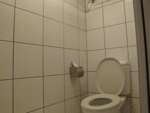a bathroom with a toilet with a white tiled wall at Oscar Inn in Petaling Jaya