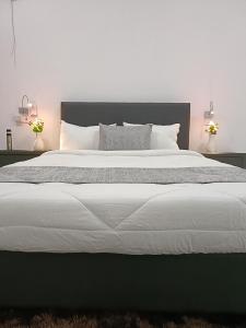 um quarto com uma cama grande com lençóis brancos e almofadas em City Centre em Mombasa