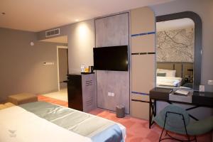 Schlafzimmer mit einem Bett, einem Schreibtisch und einem TV in der Unterkunft Skyline Tabuk Hotel in Tabuk