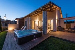Un patio trasero con jacuzzi en una terraza de madera. en Domaine de la durantie - villa avec jacuzzi, en Castelnau-de-Montmiral