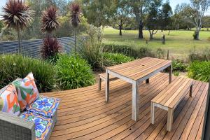 une terrasse en bois avec une table de pique-nique et un canapé dans l'établissement Fairways 1, à Coles Bay