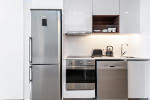 Il comprend une cuisine équipée d'un réfrigérateur en acier inoxydable et d'une cuisinière. dans l'établissement Luxurious 16 on Bree Studio Apartment - Harbour Views, au Cap