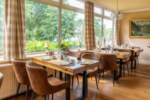 マレンテにあるHotel Holsteinische Schweiz am Diekseeの木製のテーブルと椅子、大きな窓のあるレストランを併設しています。