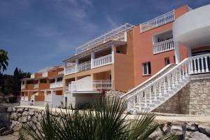 a building with white balconies and stairs on a beach at Belvedere Gerakas Luxury Suites in Vasilikos