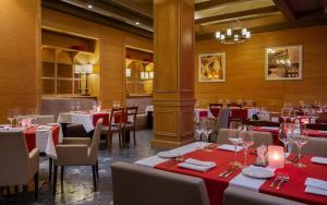 a restaurant with tables and chairs with red tablecloths at Mövenpick Hotel Krasnaya Polyana in Estosadok