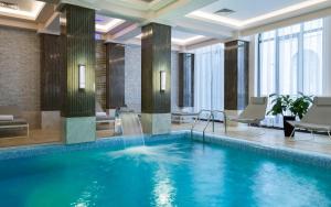 a pool with a waterfall in a hotel lobby at Mövenpick Hotel Krasnaya Polyana in Estosadok