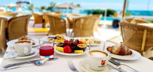stół z talerzami jedzenia i kubkami kawy w obiekcie Hotel Bellevue w mieście Pesaro