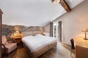 Un dormitorio con una gran cama blanca y una mesa en Hotel Aux Ecuries De La Reine, en La Gleize
