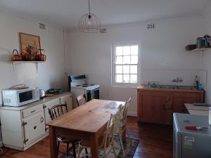 a kitchen with a wooden table and a microwave at Yardley Cottage in Colesberg