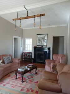 ein Wohnzimmer mit rosa Sofas und einem Tisch in der Unterkunft Yardley Cottage in Colesberg