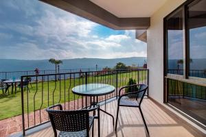 a balcony with a table and chairs and a view of the water at Mountain Breeze Resort, Mahabaleshwar in Mahabaleshwar