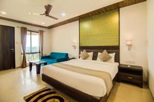 una camera con un grande letto e una sedia blu di Mountain Breeze Resort, Mahabaleshwar a Mahabaleshwar