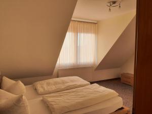 a bedroom with a bed and a window in a attic at Landhaus Braband Ferienwohnungen - Cuxhavener Straße 96 in Cuxhaven