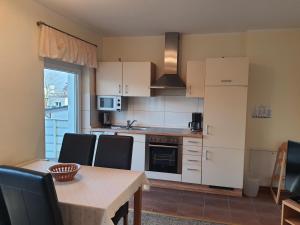 a kitchen with white cabinets and a table with chairs at Landhaus Braband Ferienwohnungen - Cuxhavener Straße 96 in Cuxhaven