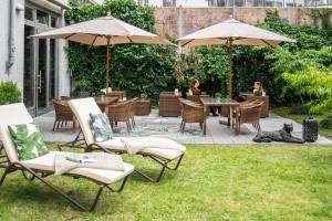 a patio with chairs and umbrellas with a dog laying on the grass at Townhouse Berlin in Berlin