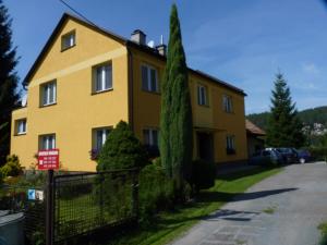 ein gelbes Haus mit einem Zaun davor in der Unterkunft Apartmán Novákovi in Náchod