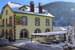 un grand bâtiment jaune recouvert de neige dans l'établissement Hotel Restaurant Du Haut Du Roc, à Basse-sur-le-Rupt