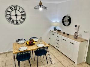 een keuken met een tafel met stoelen en een klok aan de muur bij Nouveauté - L'Oasis - T3 - 70 M2 - Jacuzzi in Saint-Denis
