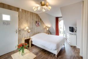 a bedroom with a white bed and a tv at Les Ormes Domaine et Resort in Epiniac