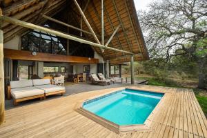 een huis met een zwembad op een houten terras bij Rhino River Lodge in Manyoni Private Game Reserve