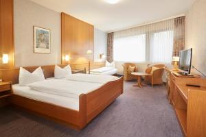 バート・ファリングボステルにあるPark Hotel Berlinのベッドとテレビが備わるホテルルームです。