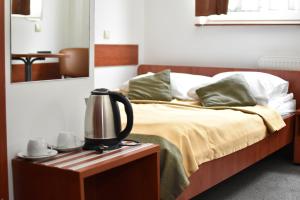 a bedroom with a bed with a kettle on a night stand at Hotel Dąbrowiak in Dąbrowa Górnicza