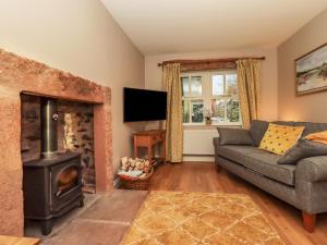 ein Wohnzimmer mit einem Sofa und einem Kamin in der Unterkunft Rose Cottage in Penrith