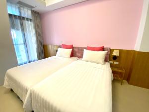 een slaapkamer met 2 bedden met witte lakens en rode kussens bij Tainan Together House in Tainan