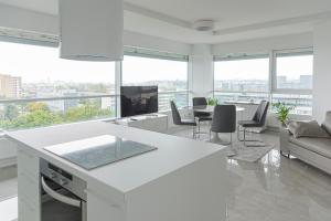 a white kitchen and living room with a table and chairs at VilniausPanorama in Vilnius