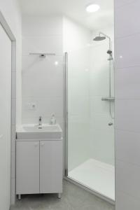 a white bathroom with a shower and a sink at VilniausPanorama in Vilnius