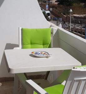 Salema Beach Apartment في ساليما: طاولة بيضاء وكرسي أخضر على شرفة