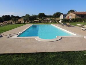 a swimming pool in a yard with chairs around it at Agriturismo Valle Martina in Saturnia